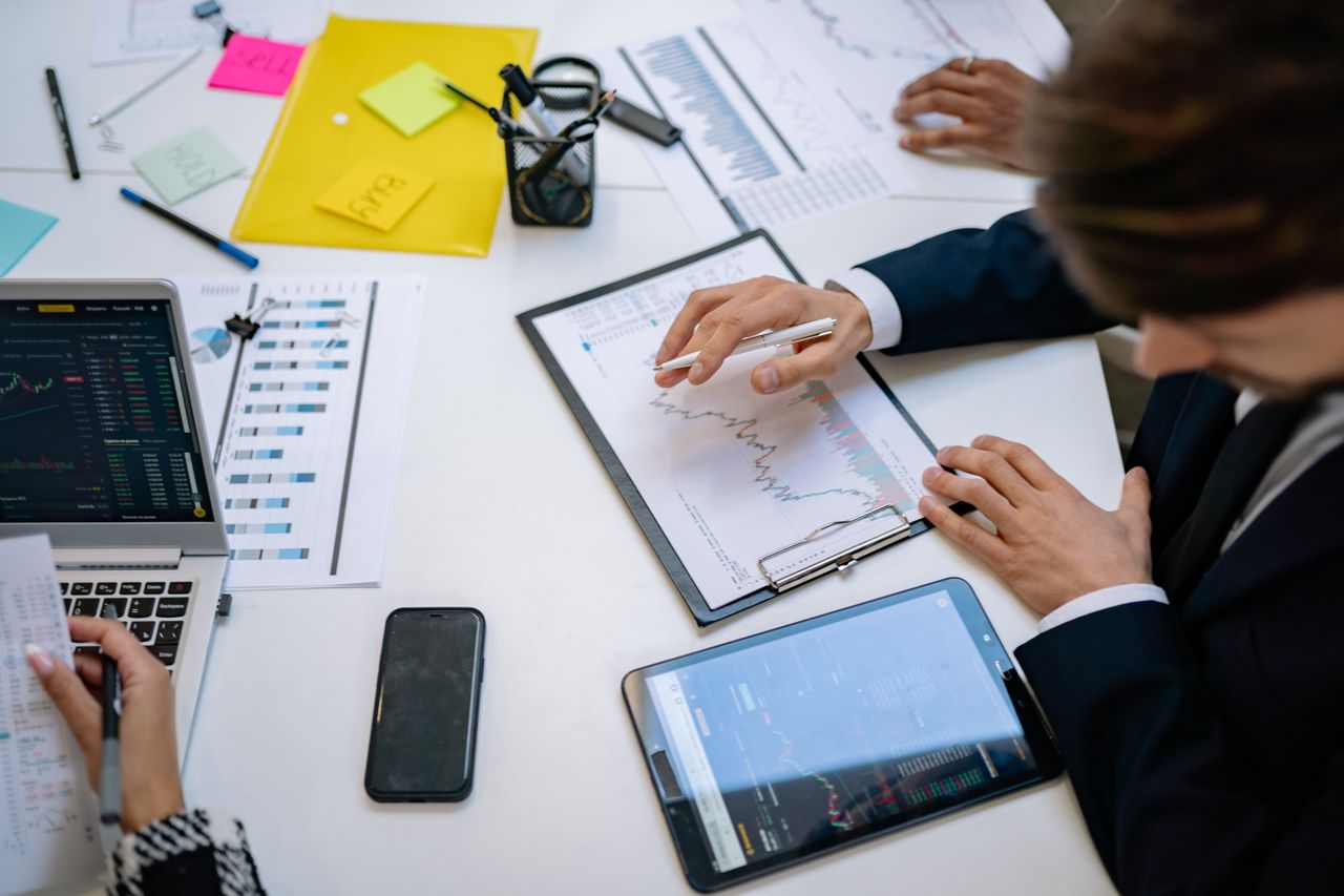 the-story Team reviewing financial charts and digital data on tablets in an office setting.